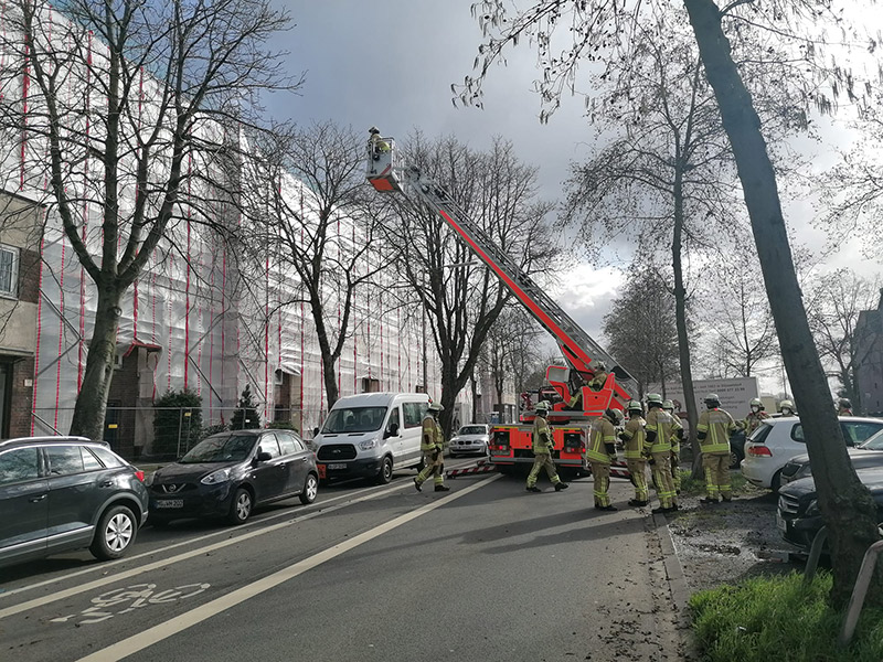 Einsatzkräfte der Feuerwehr in Aktion bei einem Einsatz an einem mit Gerüsten umgebenen Gebäude, unterstreicht die ständige Bereitschaft und Effizienz der städtischen Notfalldienste.