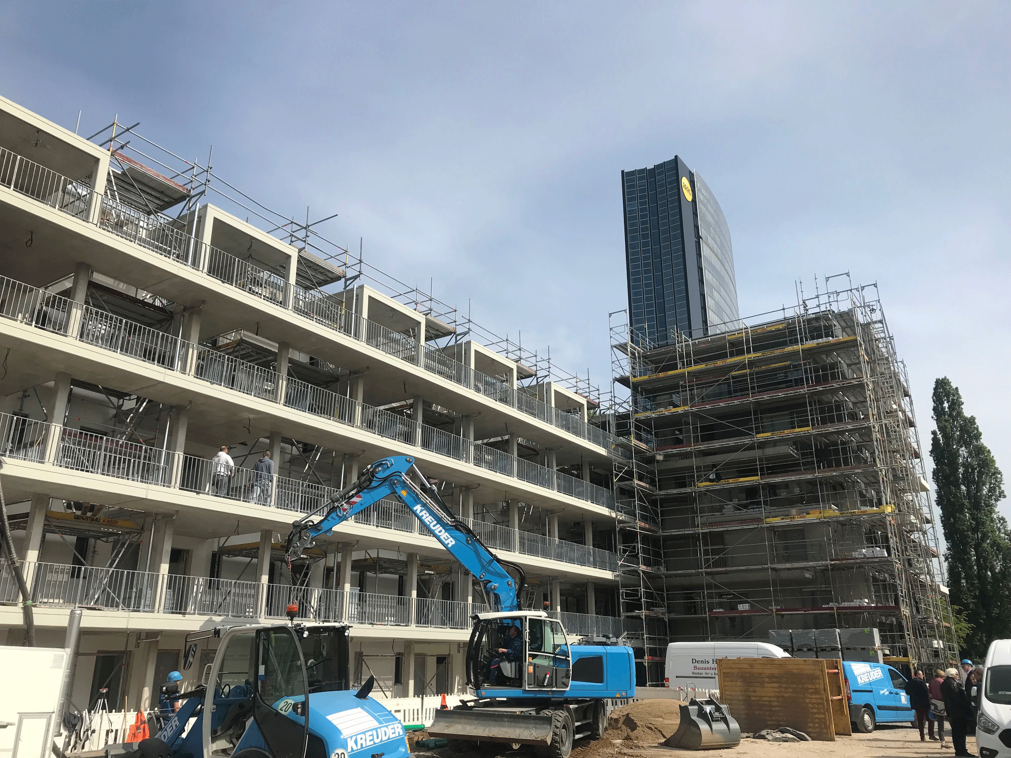 Ein Bild von einem im Bau befindlichen Mehrfamilienhaus, das die dynamische Entwicklung urbanen Wohnraums zeigt, mit einem Kran und Bauarbeitern in Aktion.